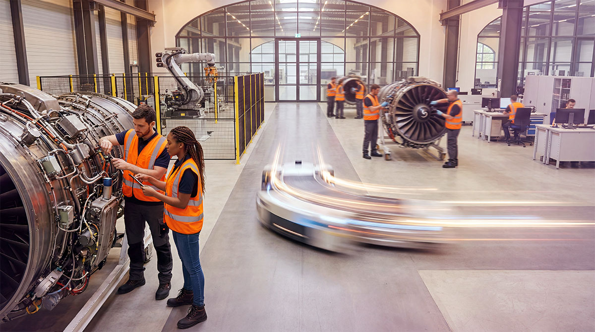 Factory workers assembling airplane engine parts on a production floor