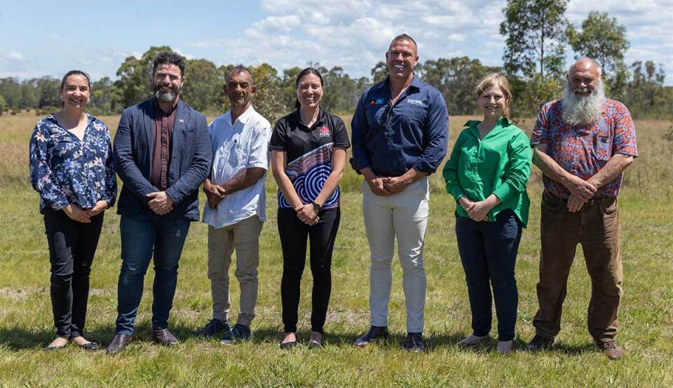 Seven people standing in a row and smiling