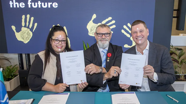 A woman and two men holding a signed document