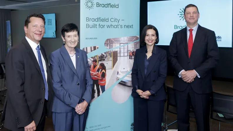 Four people stand on either side of a banner saying Bradfield City - Built for what's next