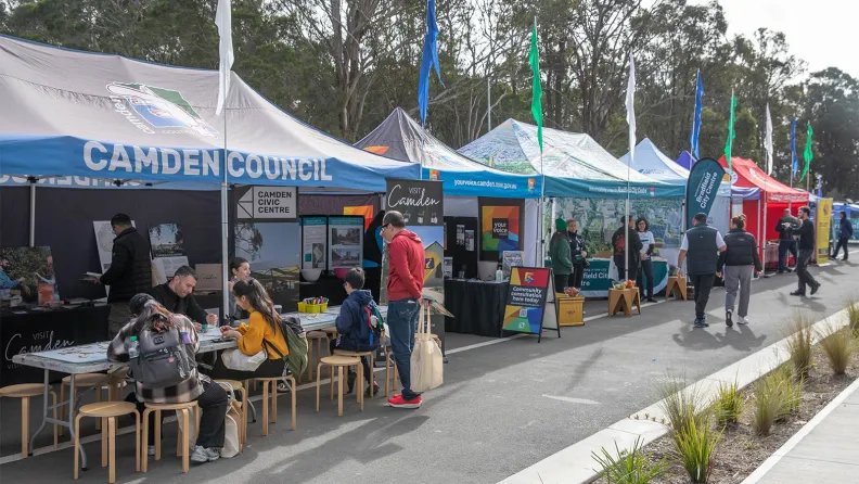 People visiting outdoor market stalls at a community event