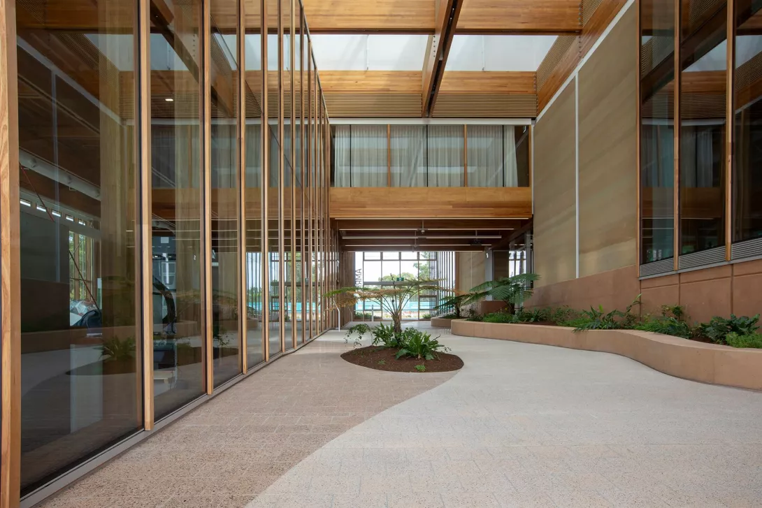 A modern, open atrium, surrounded by glass, with a garden.
