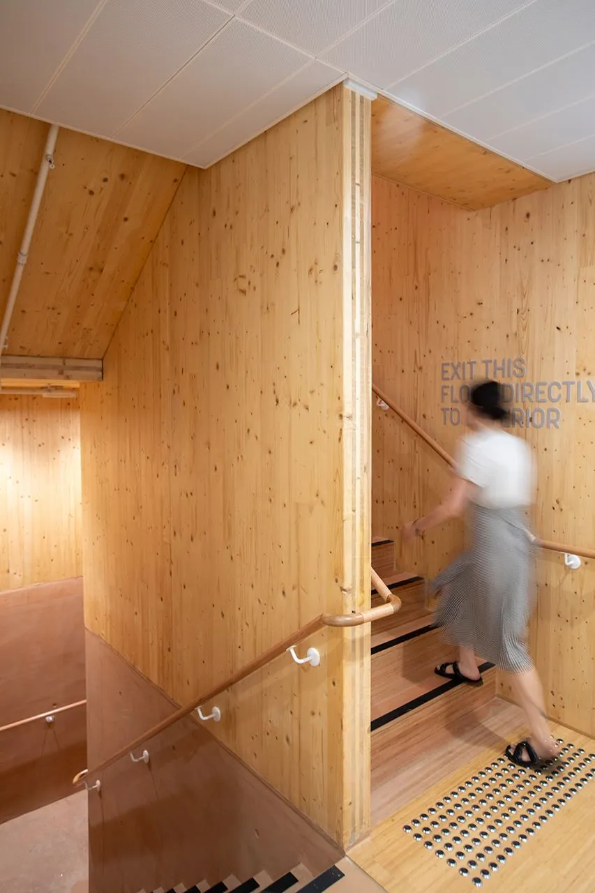 A person walking up a timber stairwell