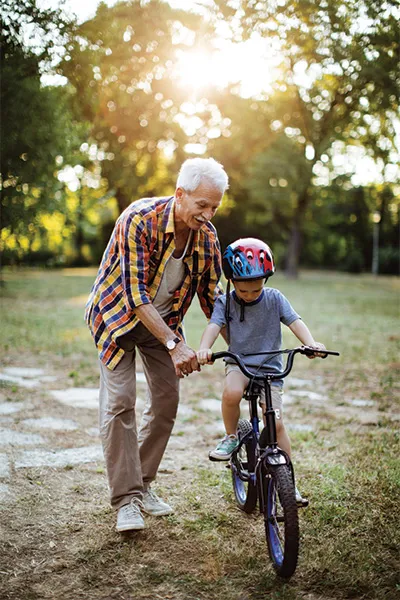 Man pushing a young child on a bike