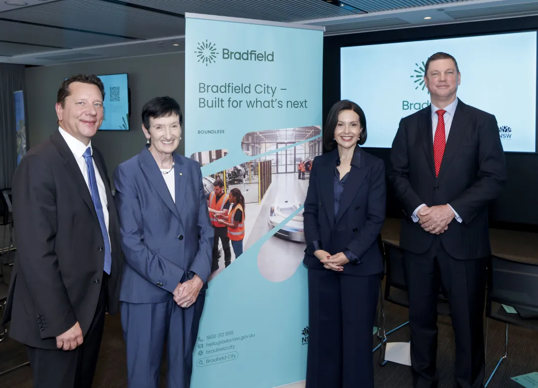 Four people stand on either side of a banner saying Bradfield City - Built for what's next