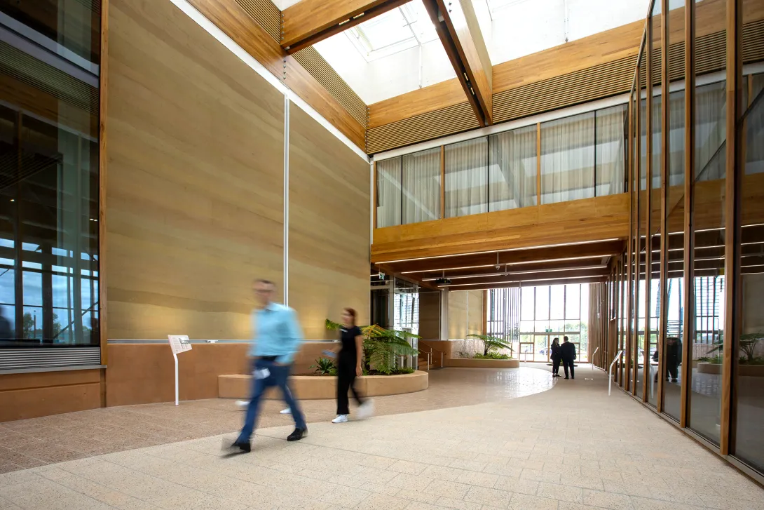 People walking through an open atrium with rammed earth walls in First Building