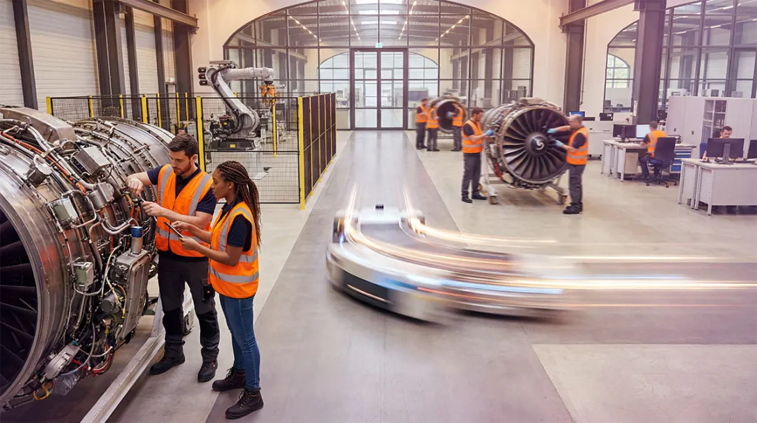Factory workers assembling aeroplane engine parts on a production floor